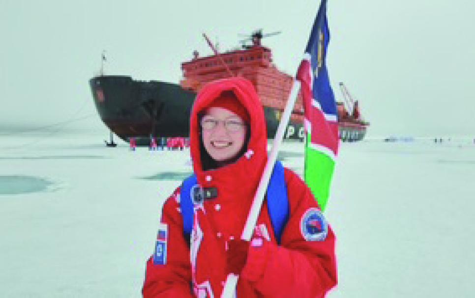Teaghan Beresford from Namibia proudly stands at the North Pole, holding her nation’s flag high amid the Arctic’s breathtaking expanse